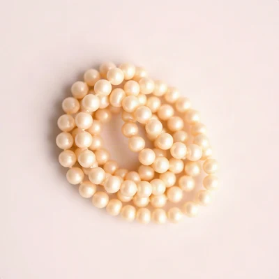 coquette pfp — string of pearls coiled elegantly, blush pink and cream, gentle film grain